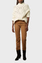 A person wearing a cream pull col montant en laine mélangée, brown pants, and black boots stands against a plain light background. The person’s face is not visible in the image.