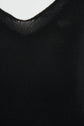 Close-up of a black knitted fabric with a shallow, rounded neckline—possibly part of a débardeur noir or a luxuriously soft débardeur cachemire for femme—set against a plain white background.