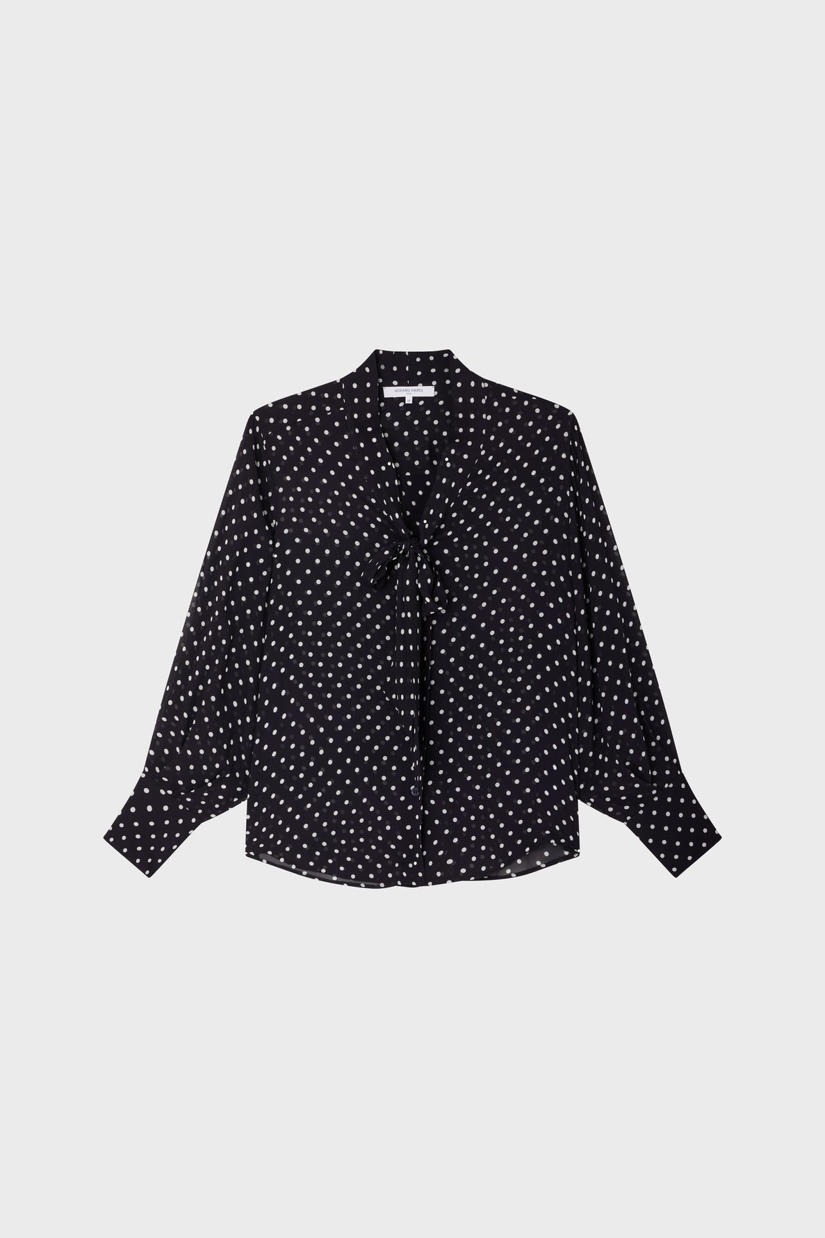 Black long-sleeve blouse with white polka dots, button-down front, and a bow tie at the collar, displayed against a plain white background.