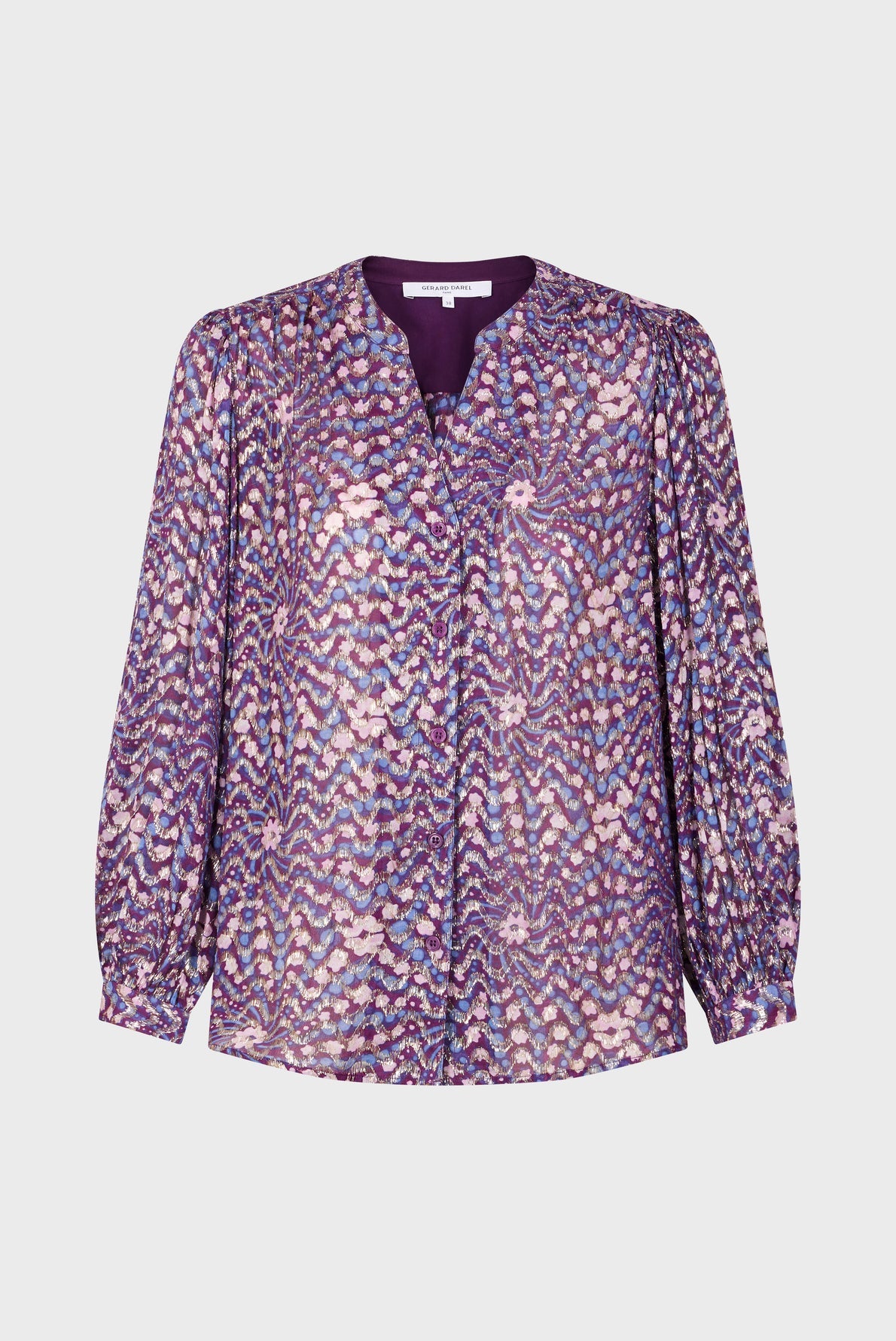 Purple long-sleeve blouse with a patterned design of pink, white, and lavender spots, a v-neckline, and buttoned cuffs, displayed on a plain white background.