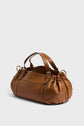 A brown leather sac à main with short handles, gold hardware, and gathered sides, crafted from cuir délicat and shown on a plain light background.