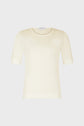 A plain, short-sleeve, cream-colored knit top with a round neckline is displayed against a light gray background.
