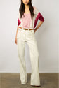 A person wearing a pink and white V-neck sweater, white high-waisted wide-leg pants with large front pockets, and a brown belt stands against a plain background.