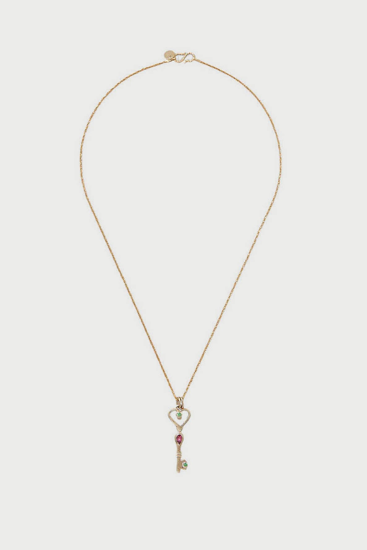 A delicate collier argent plaqué or with a thin chain features a key-shaped pendant adorned with green and red gemstones. The sautoir clé has a heart-shaped top, fine details, and an elegant touch reminiscent of a pendentif tourmaline rose.