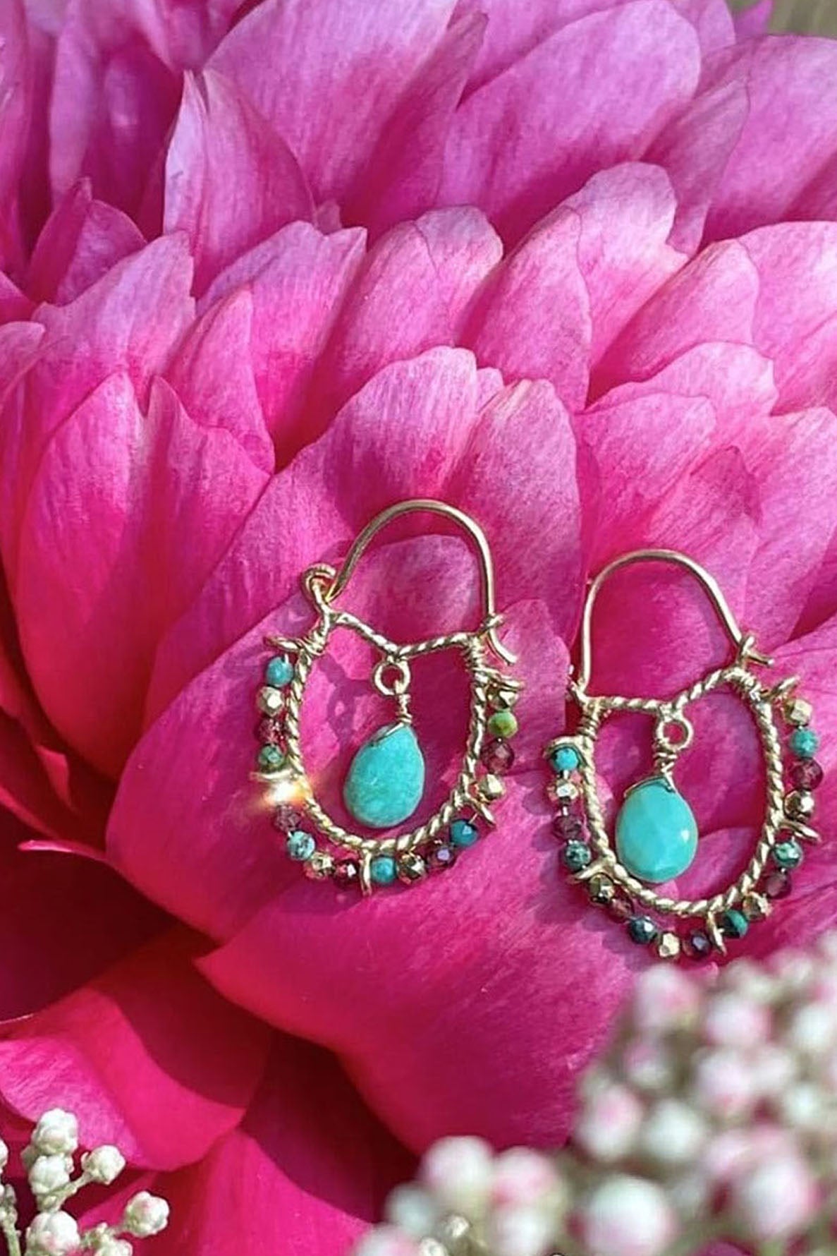 A pair of boucles d’oreilles créole in argent 925, adorned with turquoise and bead accents, displayed on a vibrant pink peony flower.